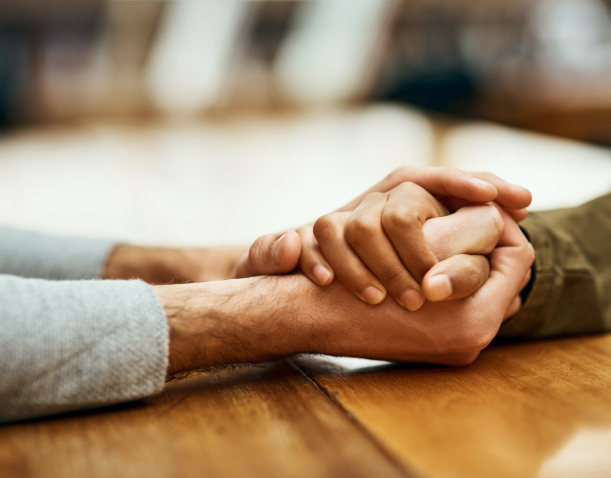 two hands of one individual holding the hand of another in a supportive manner